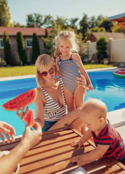 Family eating watermelon by the swimming pool